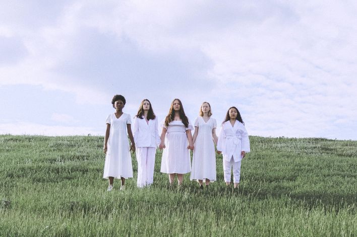 Women Holding Hands While Standing on Green Grass Field Under White Clouds