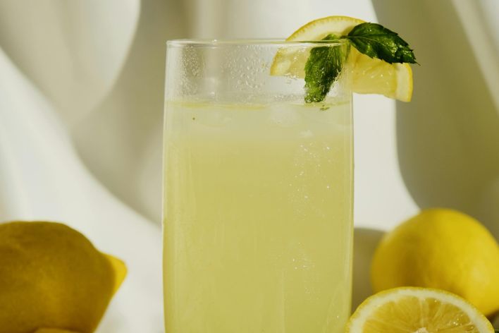 Cool glass of lemonade with lemons and mint garnish, perfect thirst-quencher.